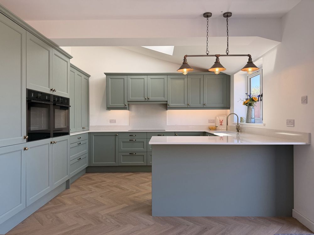 A green shaker CEK kitchen with brass pendant lights