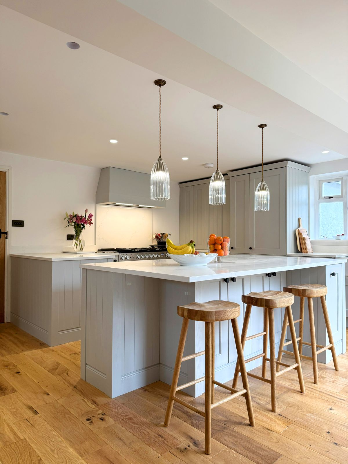 The island with 3 oak stools under glass pendant lights