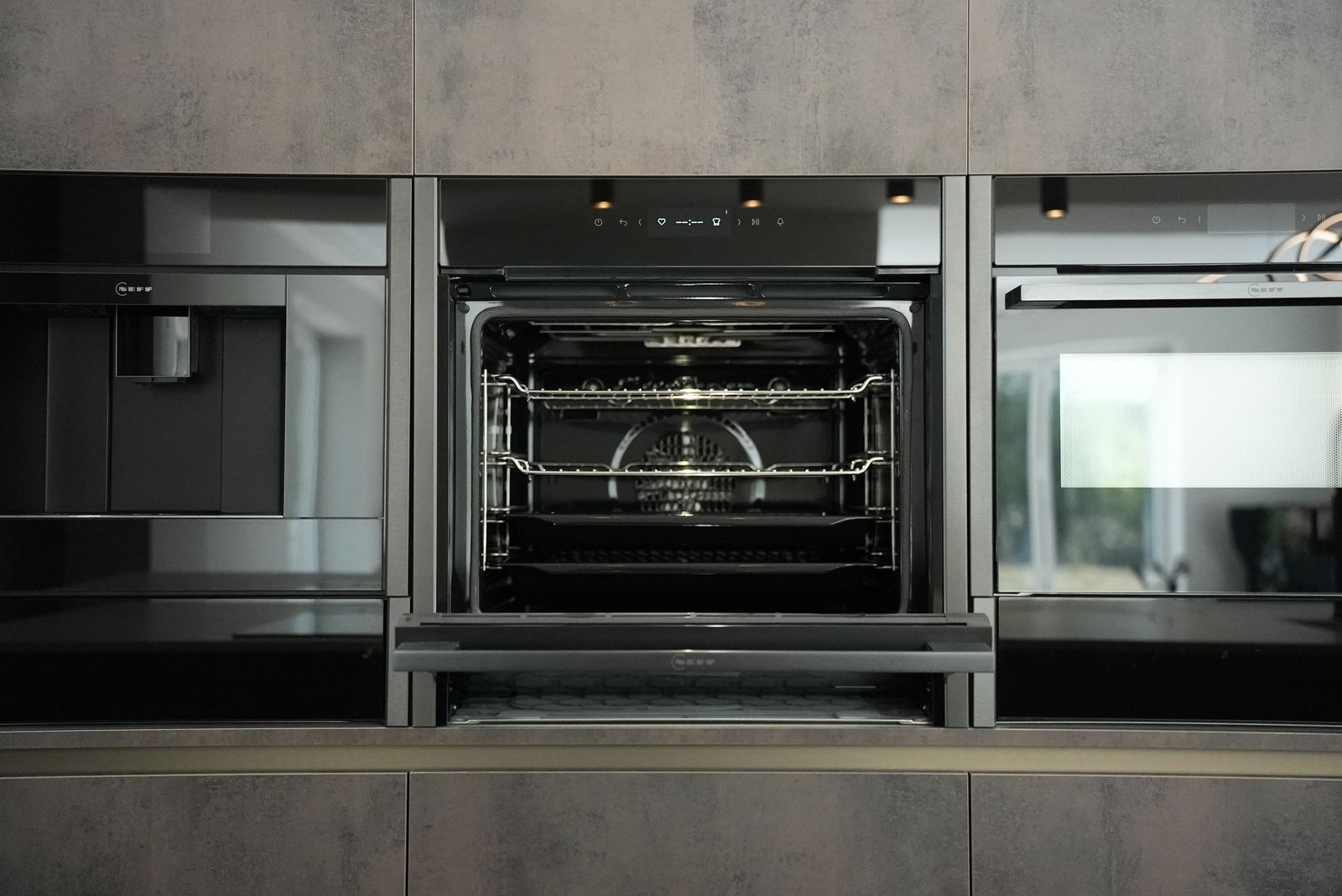 Built-in ovens, coffee machine and warming drawer set into tall dark units