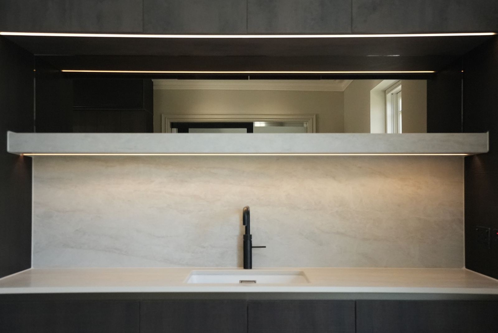 Dresser-style recess with a lit shelf, mirrored back and stone worktop