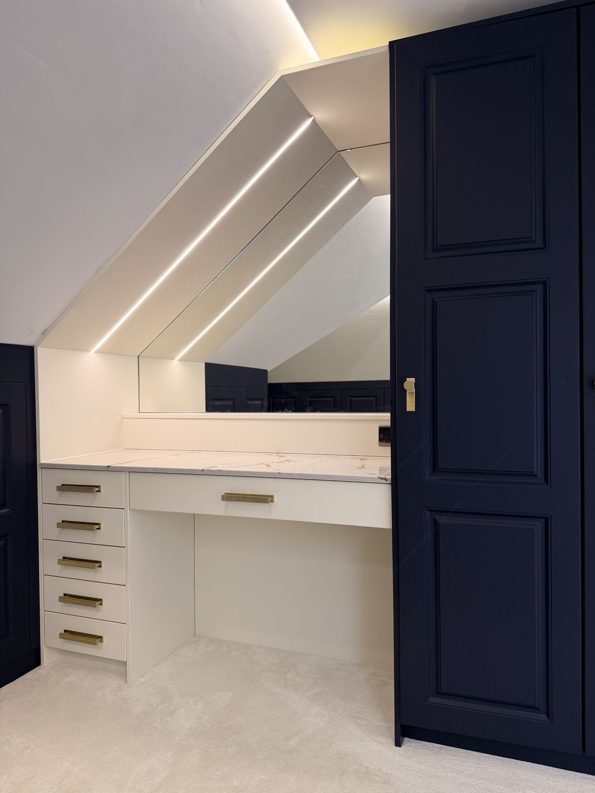 An alabaster dressing table beside a tall navy wardrobe