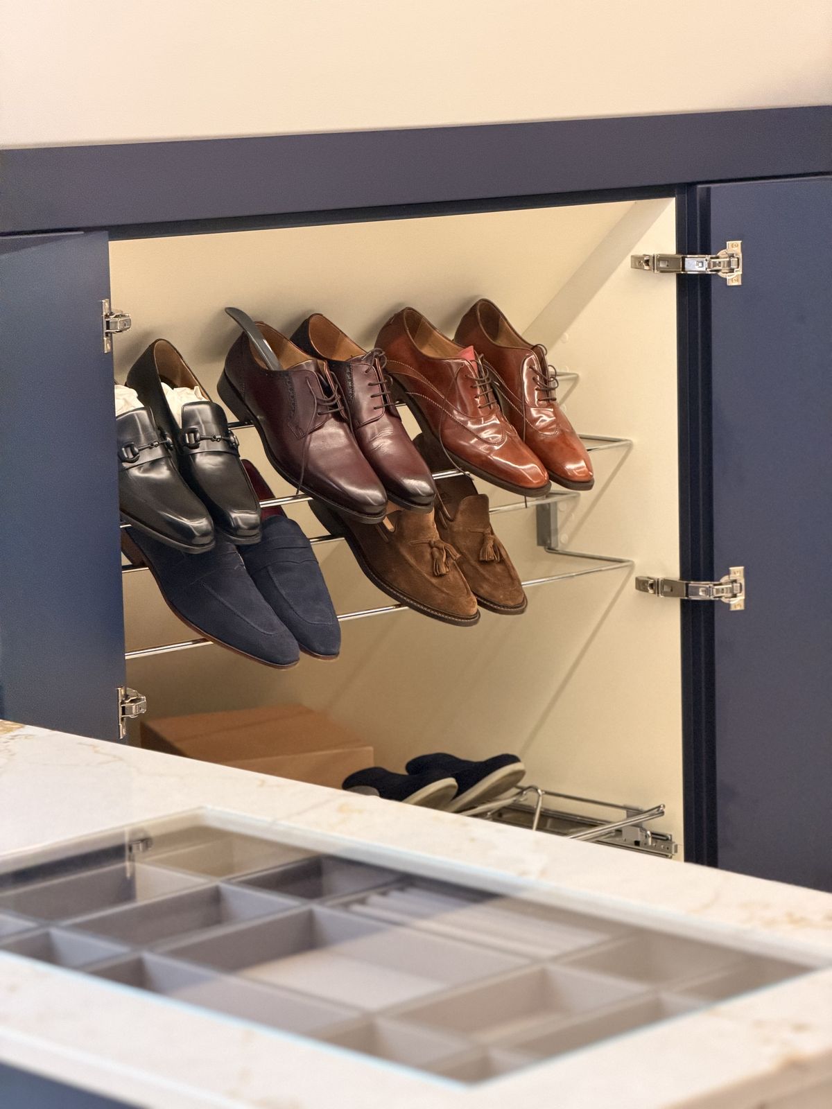 Lit shoe shelves behind a navy door
