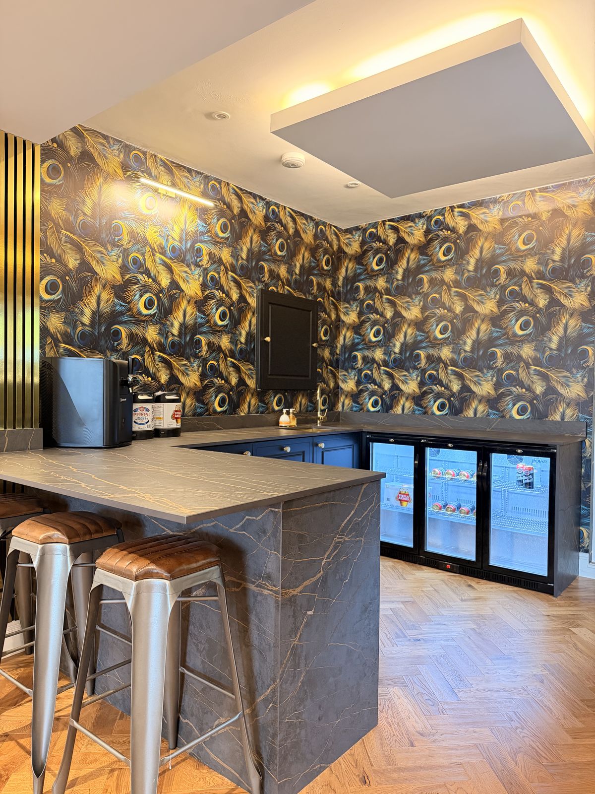 A home bar with a Dekton worktop, drinks fridges and feature wallpaper