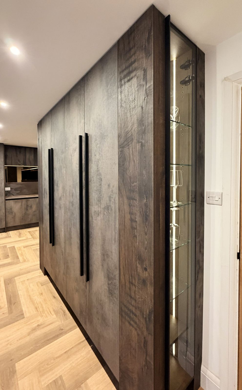 Full-height cabinetry with a glazed display door and long black handles