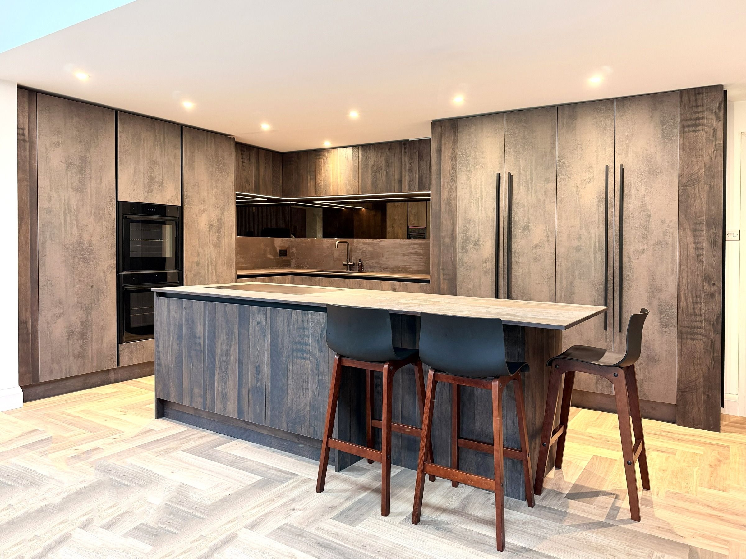 An open-plan kitchen with tall bronze-brown units and an island