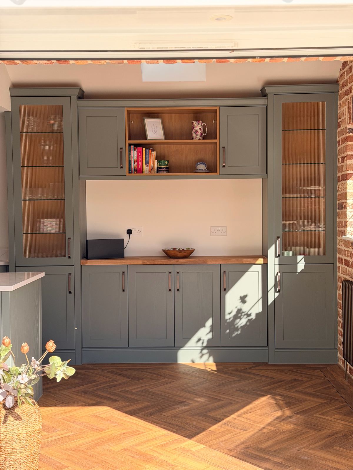 A sage green kitchen island in a new brick extension