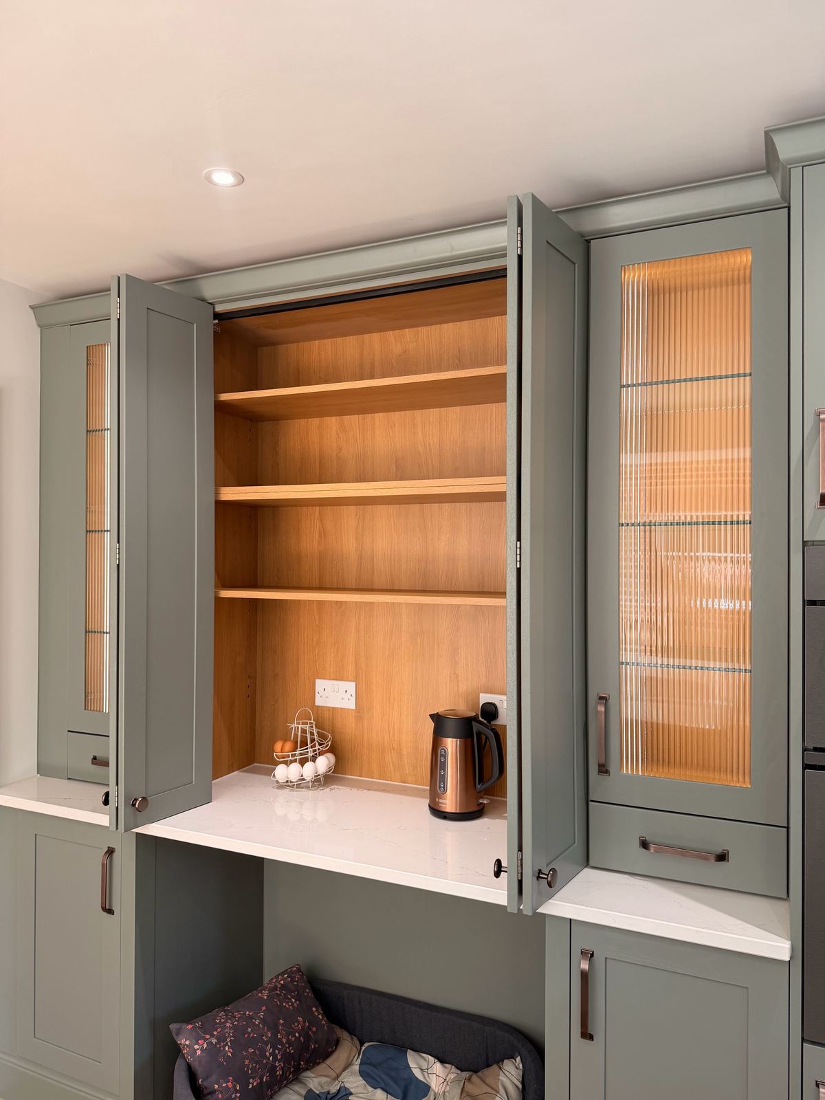 Coffee station cabinet opened to oak shelves with a dog bed below