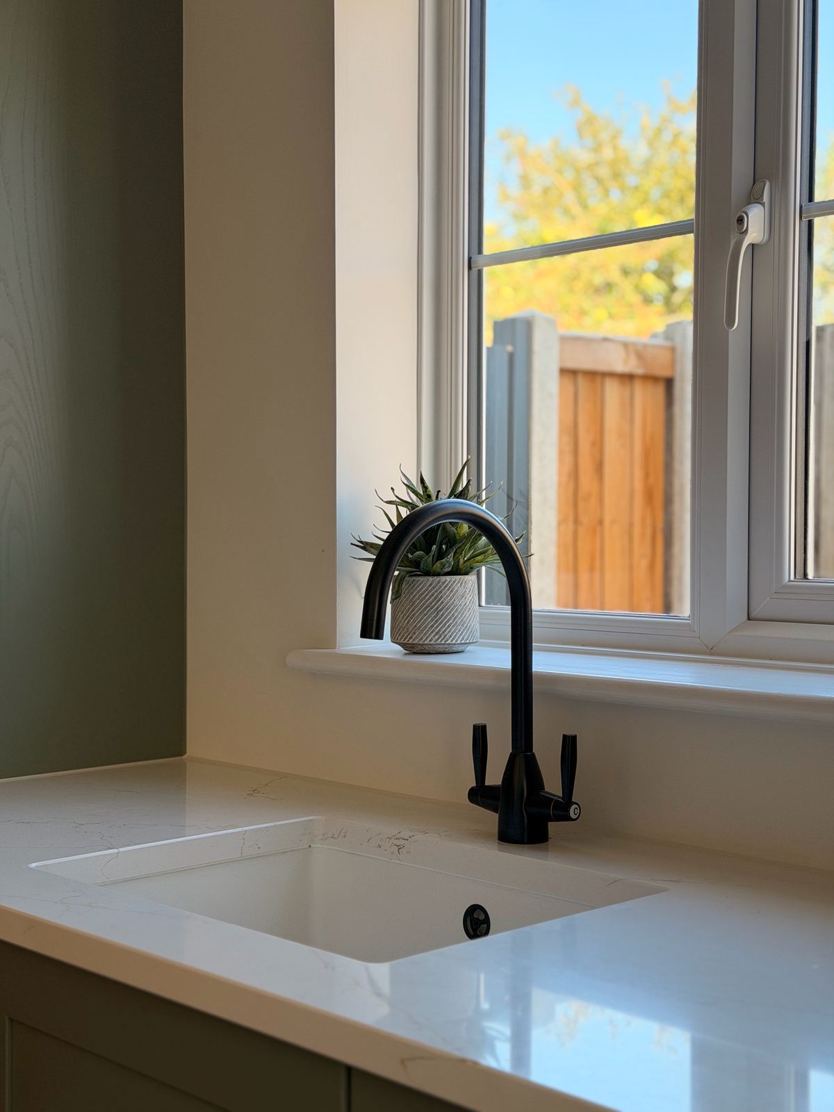 Utility room sink and black tap by a window